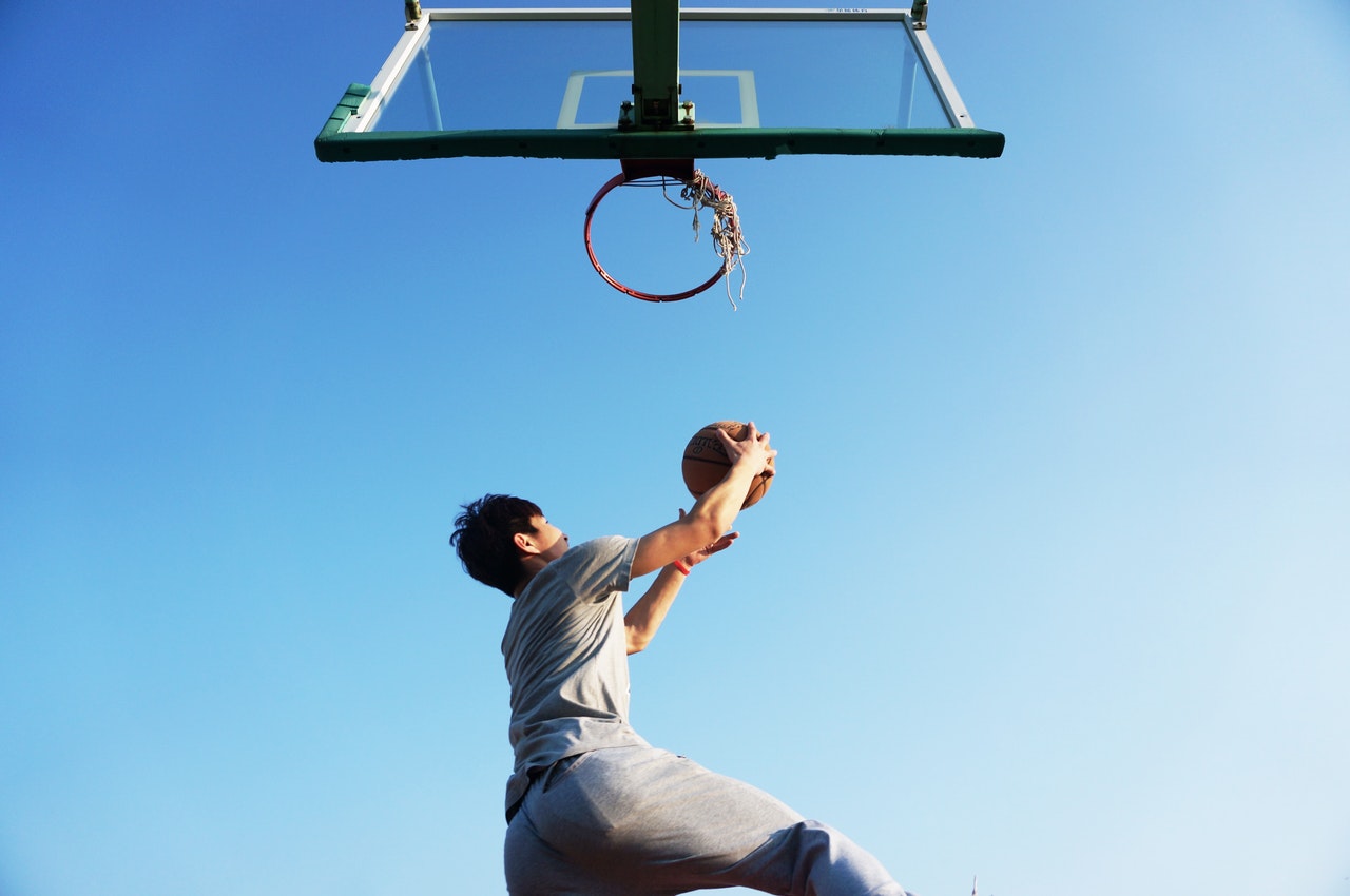 A man about to slam-dunk a ball into a net to represent goals from Locke's Goal Setting Theory